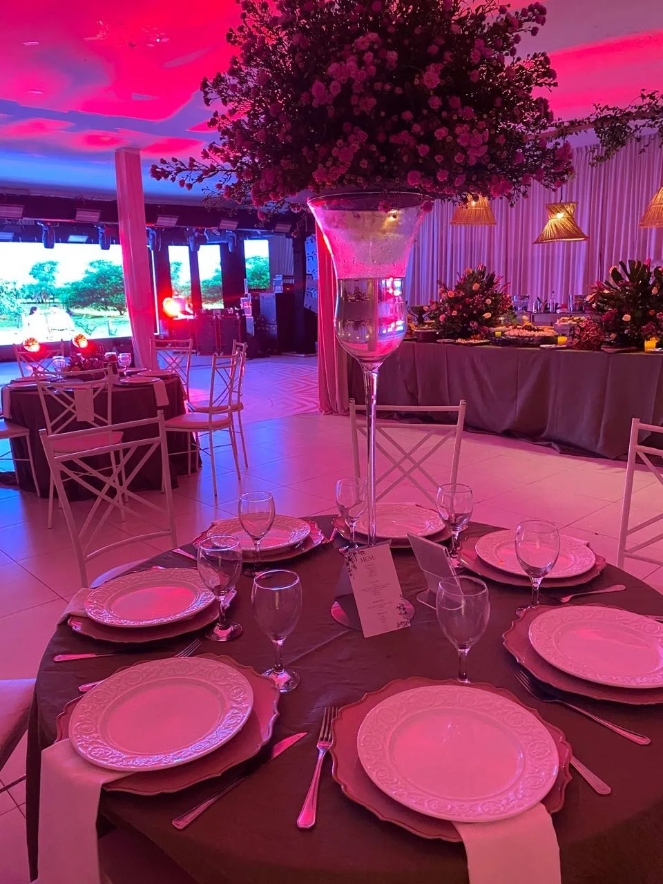 Mesa posta com pratos, taças e arranjo floral alto