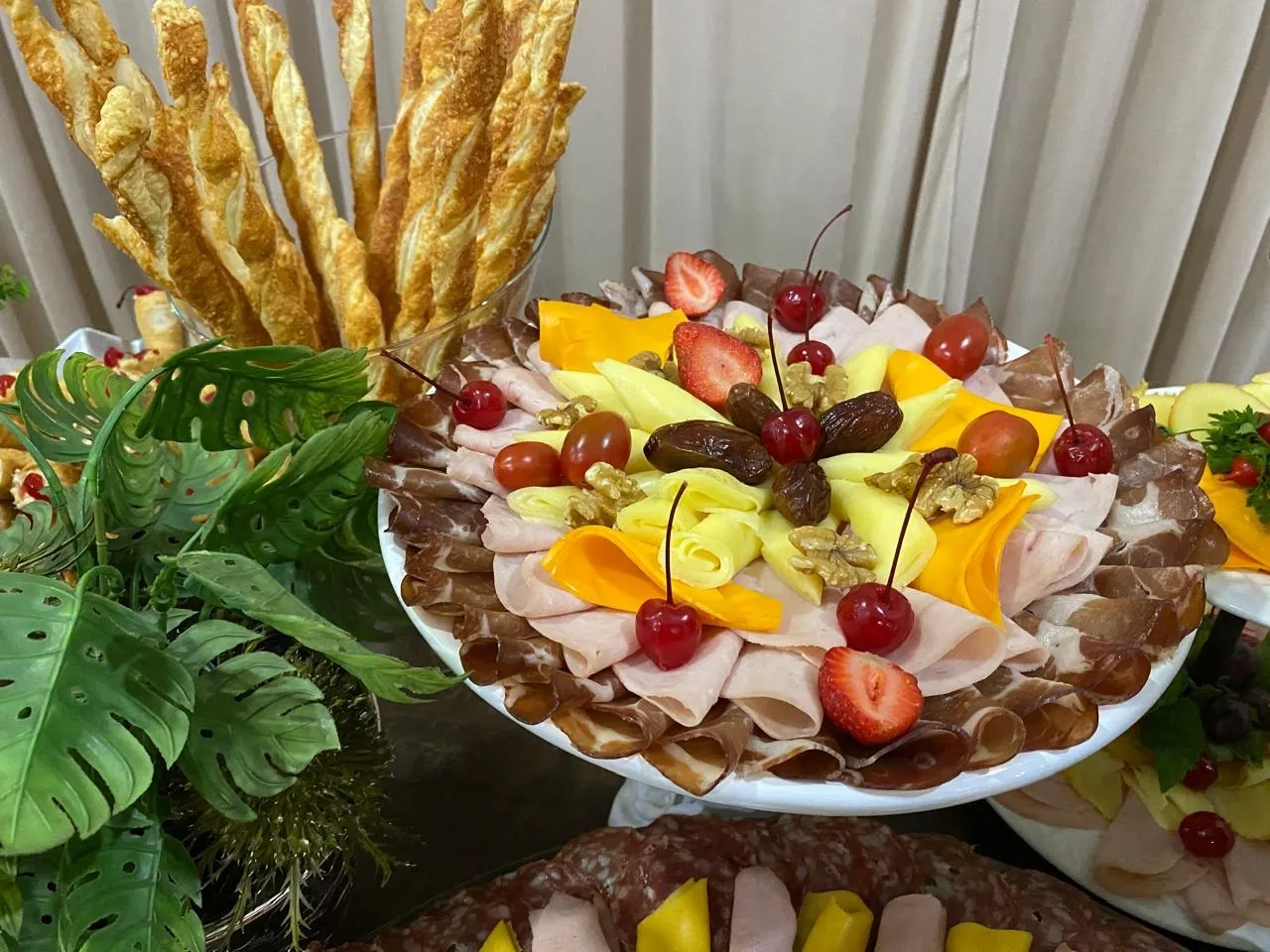 Frios e frutas com palitos de pão e folhagens