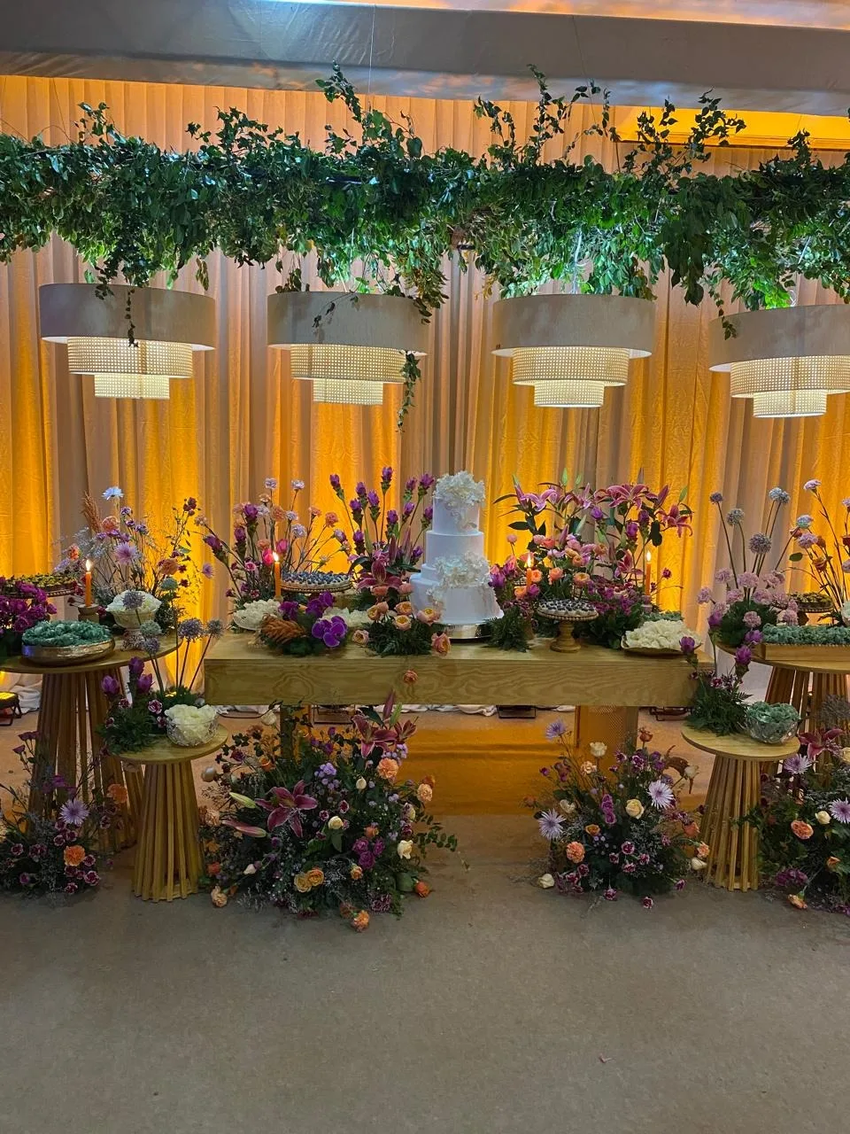 Salão de evento com mesa de bolo e flores